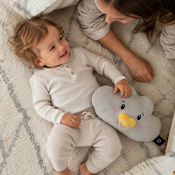 Kleinkind liegt mit seiner Mutter auf einem hellen Teppich und hält das Lenabie Lina der Wolke. Das interaktive Audio-Kuscheltier für Kinder schafft Geborgenheit und begleitet mit Hörspielen, Musik und altersgerechten Geschichten im Familienalltag.